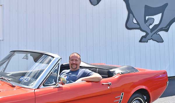 Jimmy Dinsmore siting in a 1965 Mustang at the Mustang Museum